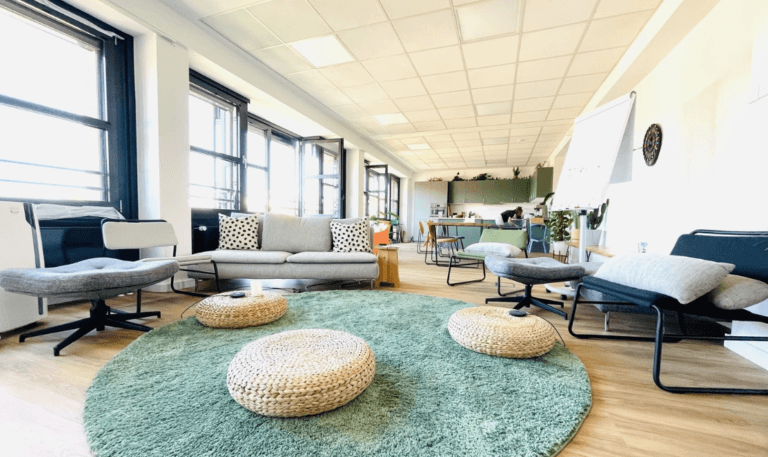 Modern coworking space with cozy seating, green rug, and natural light. Ideal for productive work.