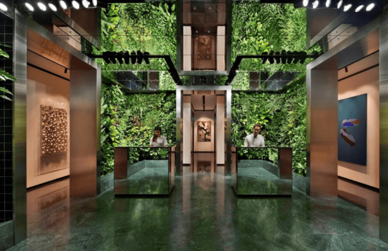 Modern office entrance with greenery and sleek design, featuring reception desks.