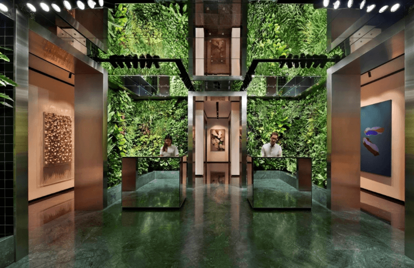 Modern office entrance with greenery and sleek design, featuring reception desks.