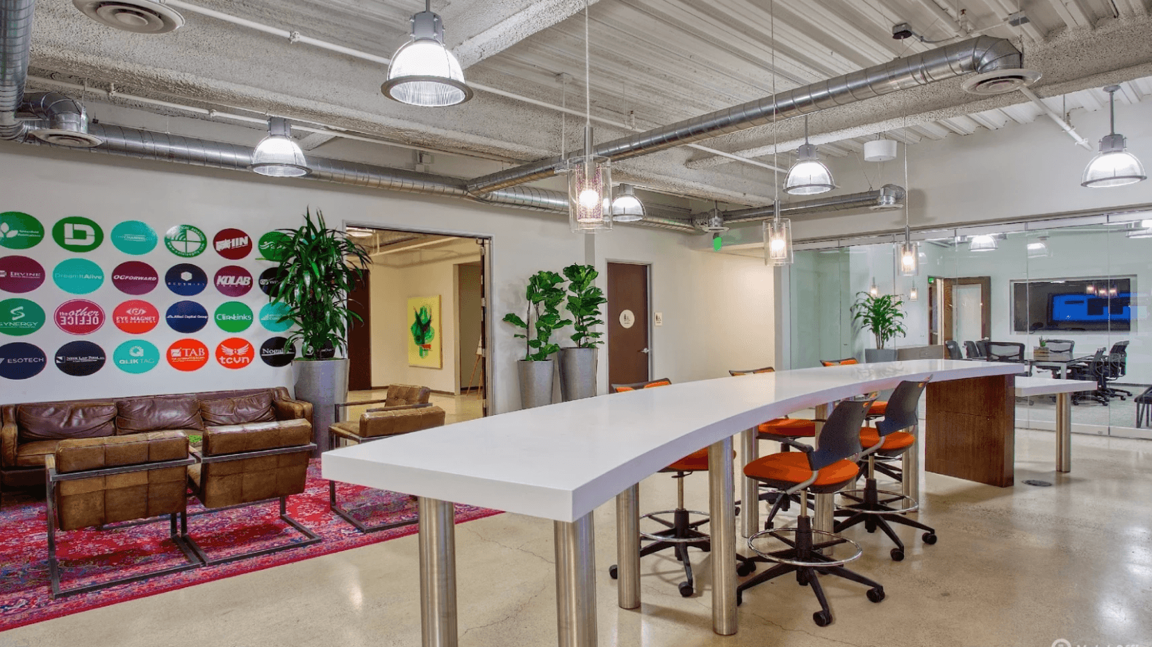 Creative coworking space with high desks, lounge area, exposed ceiling, and modern industrial design.